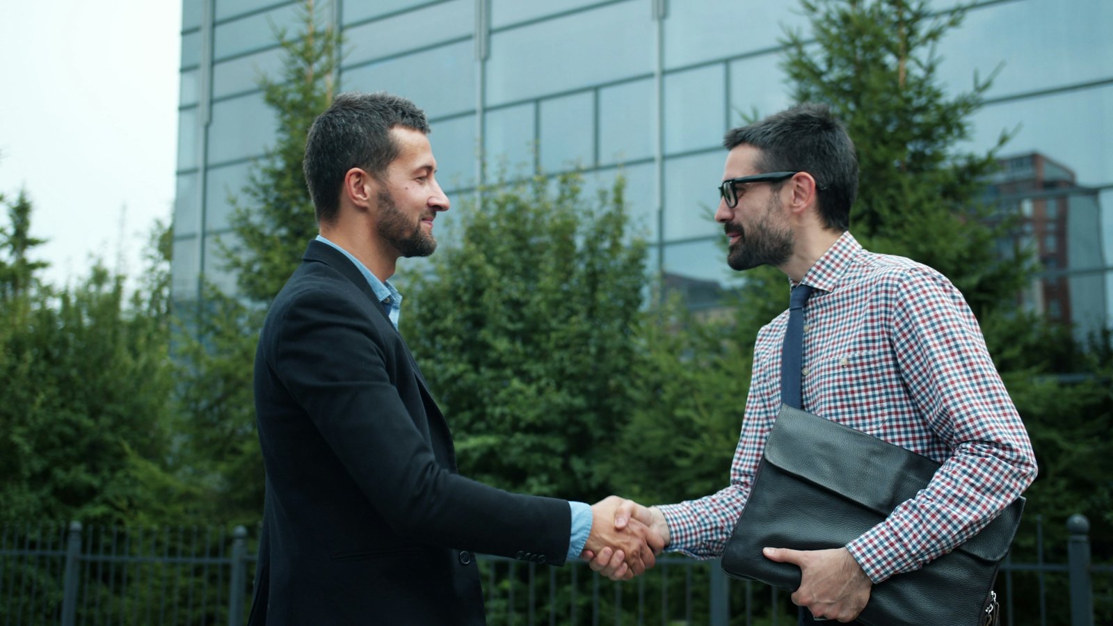 Builder and homeowner shaking hands at a house site representing integrity and trust